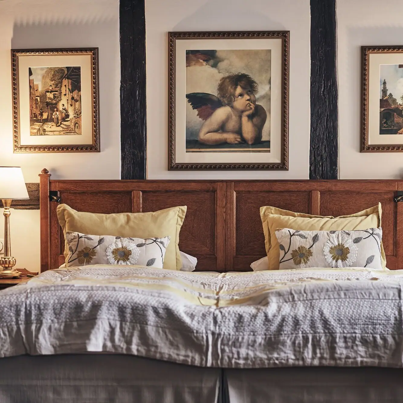 Bett mit Holz-Kopfteil und zwei gerahmten Bildern an der Wand.