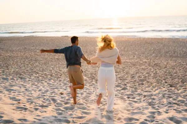 Ein Mann und eine Frau laufen am Strand.
