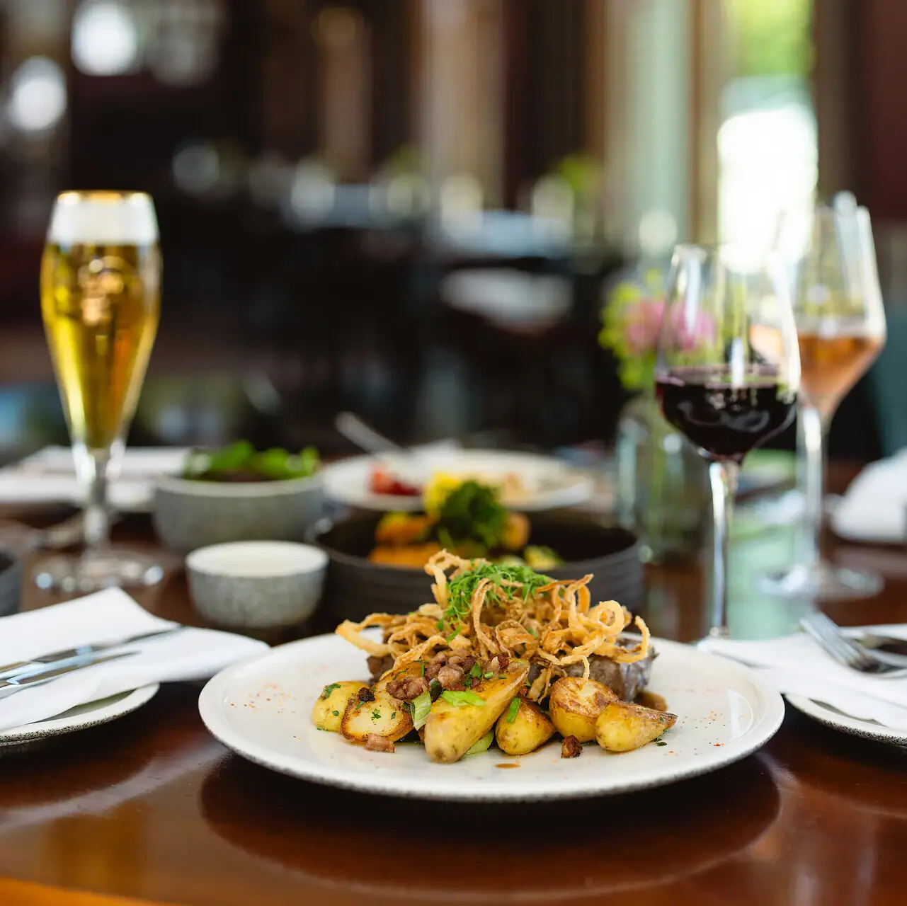 Gastronomie in Travemünde Ein Teller mit Essen auf einem Tisch, begleitet von einem Weinglas.