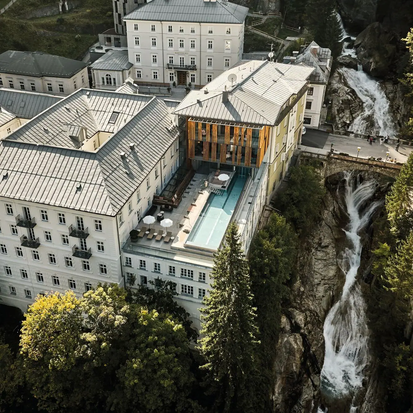 Straubinger Grand Hotel Ein Gebäude mit Pool und Wasserfall im Freien, umgeben von Bäumen.