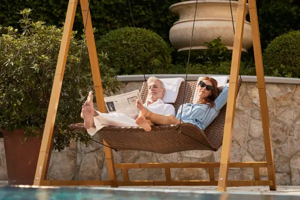 Schaukel am Pool Ein Mann und eine Frau liegen in einer Hängematte am Pool.