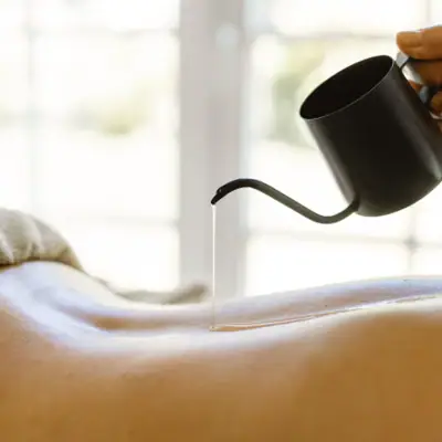 Anwendungen Eine Person gießt Öl auf einen Rücken.