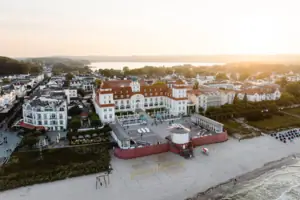 Kurhaus Binz Strand mit Gebäuden und einem Gewässer im Hintergrund.