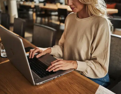 Eine Frau sitzt an einem Tisch und benutzt einen Laptop.
