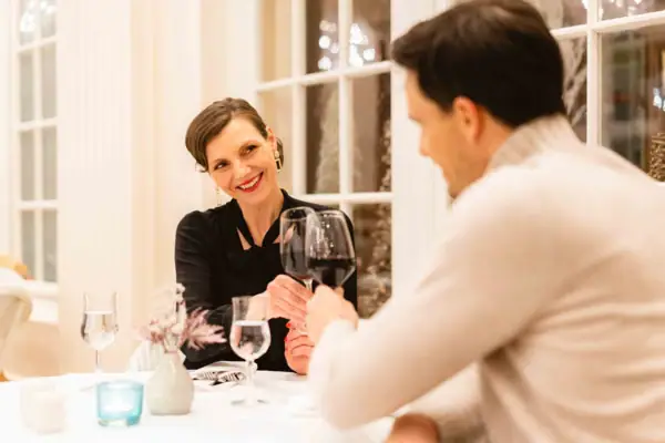Restaurantgäste A-ROSA Travemünde Ein Mann und eine Frau sitzen an einem Tisch mit Weingläsern und stoßen an.