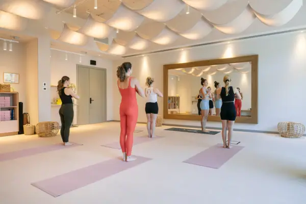 Yoga-Stunde im A-ROSA Gardasee Mehrere Gäste beim Yoga im lichtdurchfluteten Studio des A-ROSA Gardasee mit großen Spiegeln und warmem Ambiente.