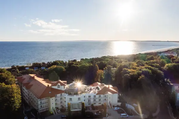 A-ROSA Heringsdorf Ein Gebäude mit Bäumen und Wasser im Hintergrund.
