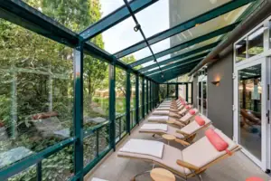 Wintergarten Ruheraum Eine Reihe von Liegestühlen in einem Raum mit Glaswänden.