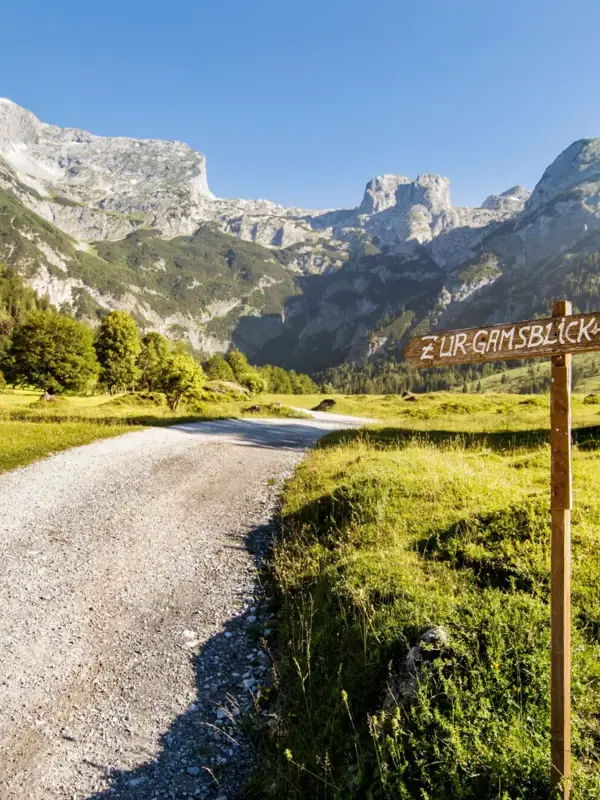 Ein Schild auf einem Feldweg in einer bergigen Landschaft.