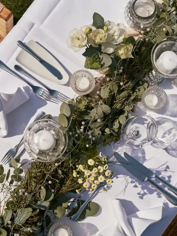 Ein Tisch mit weißem Tischtuch, Kerzen und Blumen.