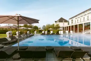 Außenpool Großes weißes Gebäude mit Pool und Bäumen im Vordergrund.