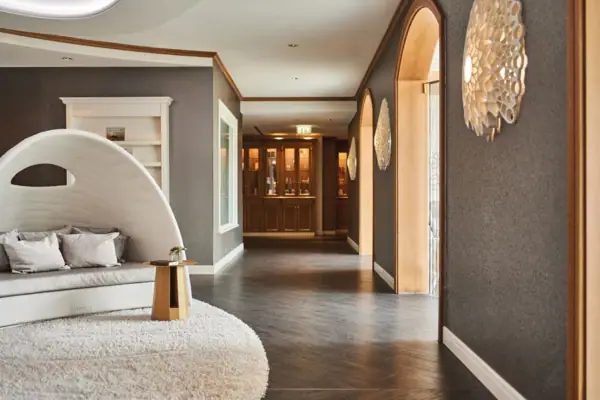 Spa Kurhaus Binz Der Eingang zum Spa Bereich im Kurhaus Binz mit weißem Teppich und rundem Stuhl.