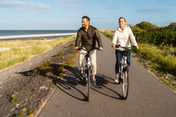 Fahrradtour am Deich Ein Mann und eine Frau fahren auf einer Straße Fahrrad.