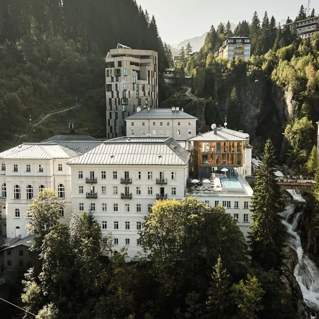 Eine Gruppe von Gebäuden mit Bäumen und Bergen im Hintergrund.