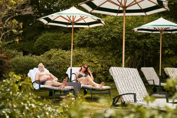 Ein Mann und eine Frau sitzen auf Liegestühlen unter Sonnenschirmen.