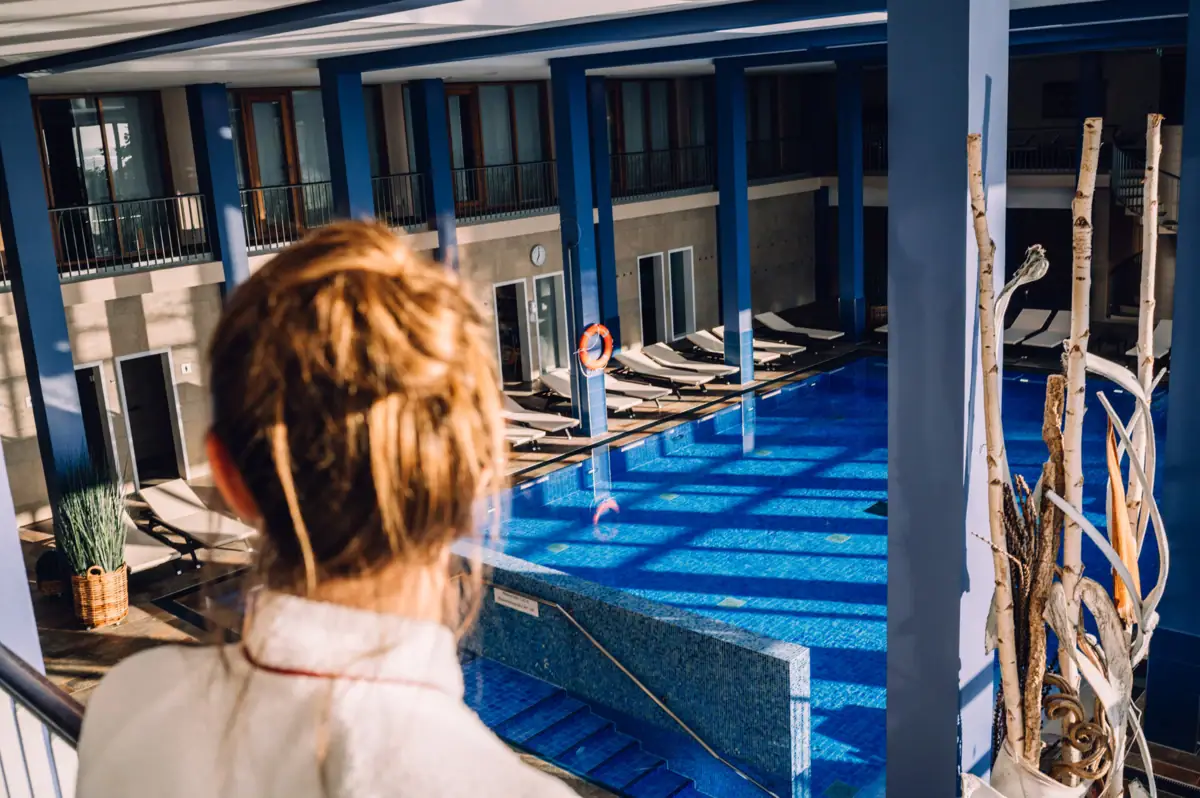 Wellnesshotel Eine Person blickt auf einen Swimmingpool.