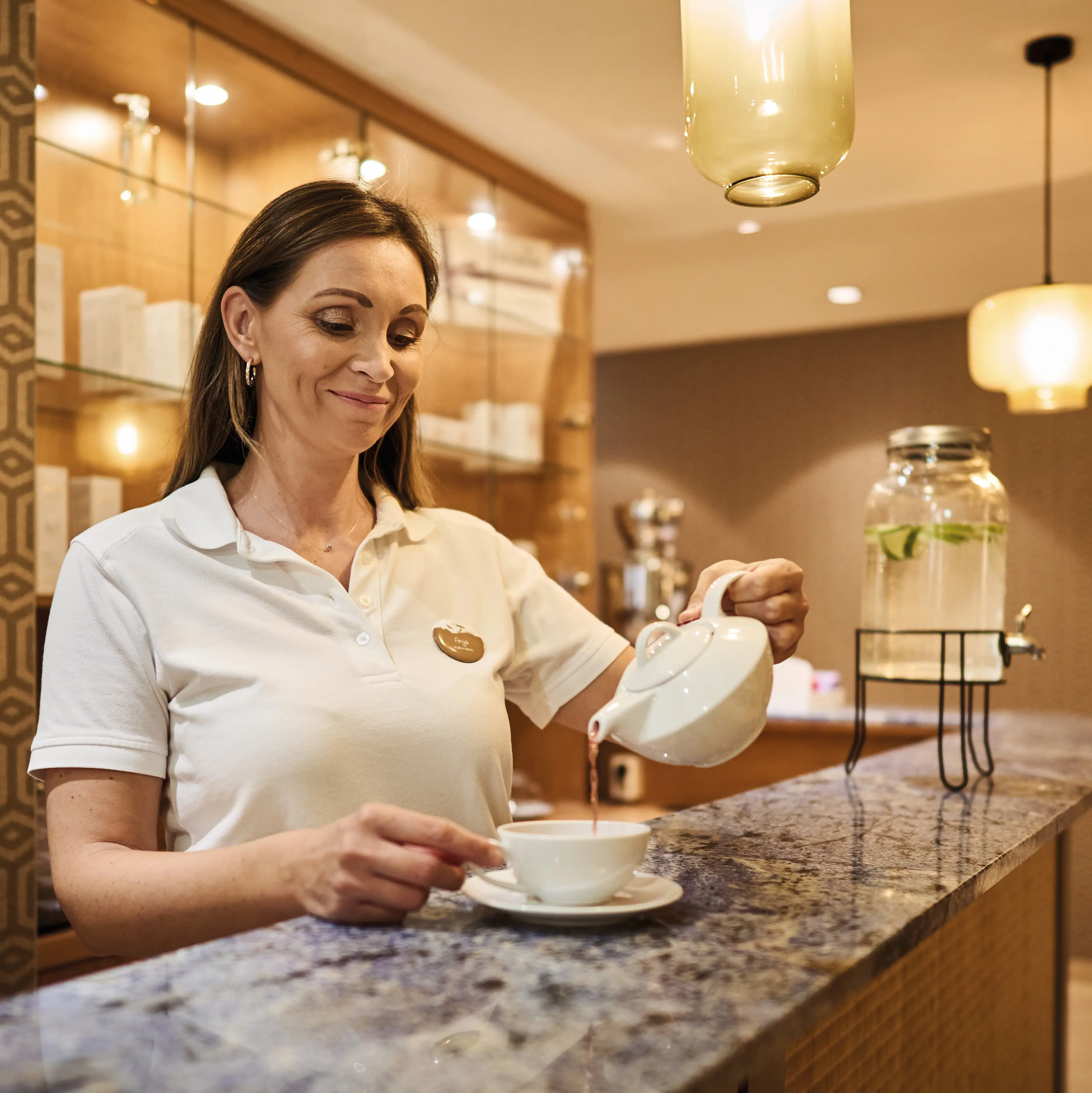 Eine Frau gießt Tee in eine Teetasse am Empfangstresen.