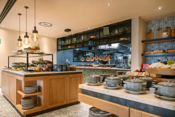 Buffetbereich des A-ROSA Gardasee Küche mit vielen Geschirr- und Kochutensilien auf der Arbeitsplatte.