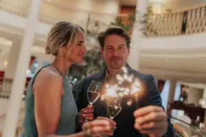 Silvester im A-ROSA Strandidyll Heringsdorf Ein Mann und eine Frau halten Weingläser.