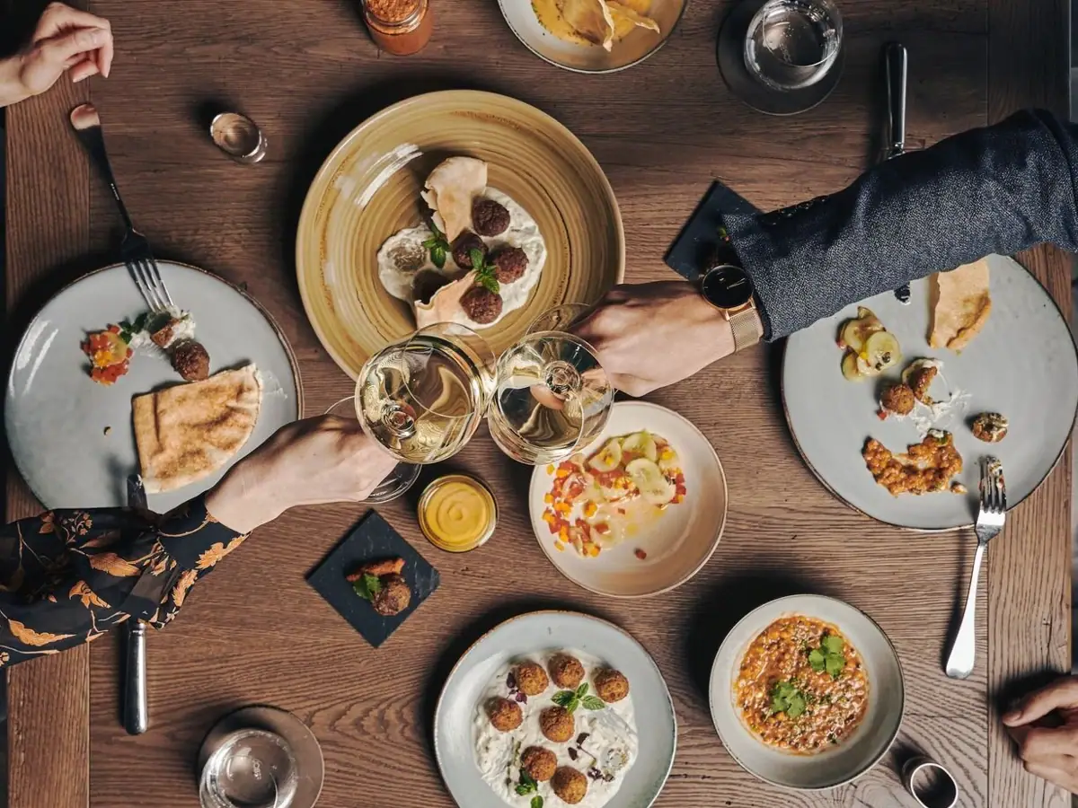 Eine Gruppe von Menschen sitzt an einem Tisch mit Tellern voller Essen aus der Vogelperspektive..