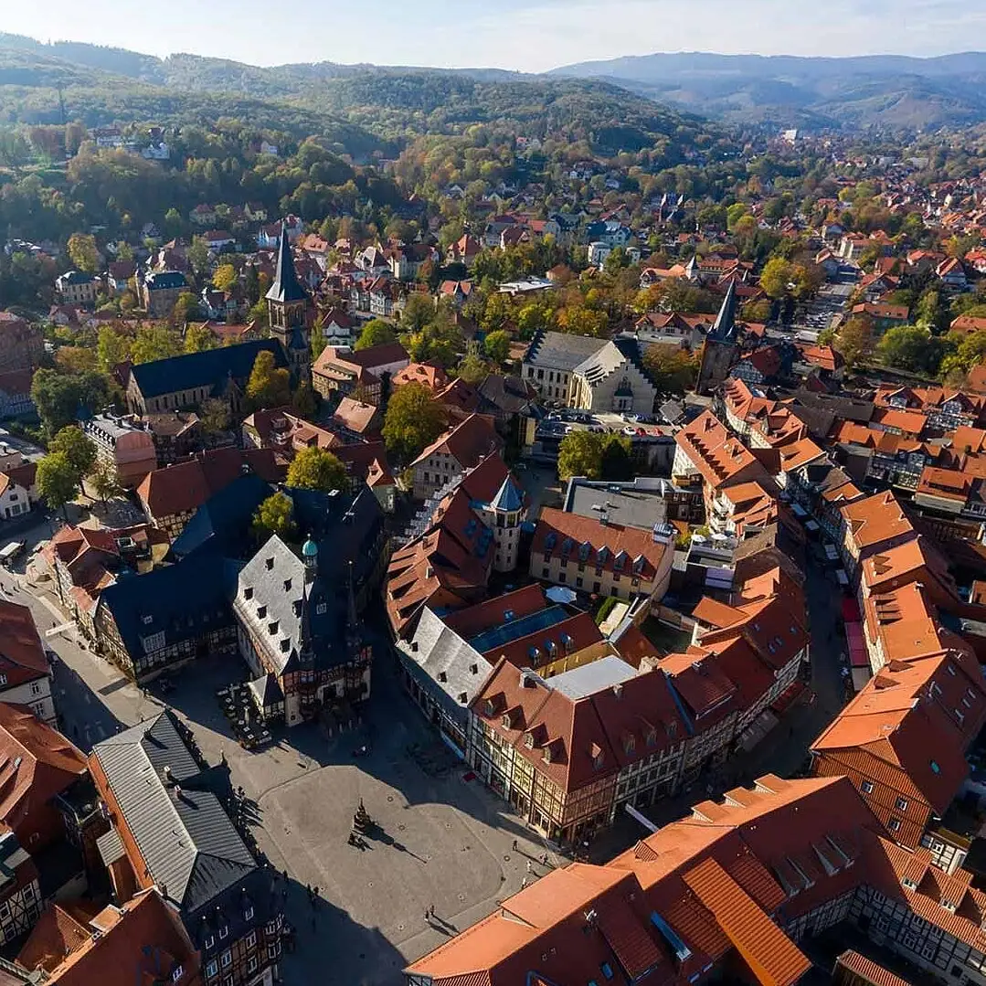 Wernigerode von oben Luftaufnahme einer Stadt mit Häusern, Bäumen und Bergen im Hintergrund.