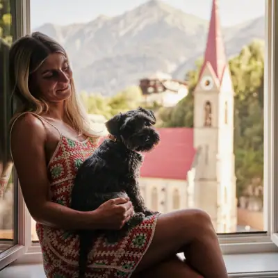 Eine Frau sitzt mit einem Hund auf einer Fensterbank.