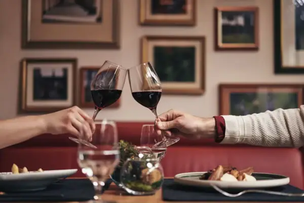 Anstoßen mit Wein Zwei Personen stoßen mit Weingläsern in einem Restaurant an.