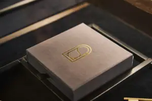 Schachtel Graue Schachtel mit goldenem Logo darauf