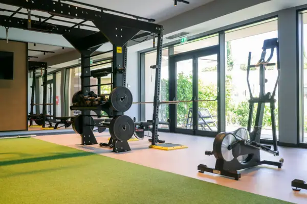 Cardio-Bereich im Fitnessstudio Cardio-Geräte wie Ergometer im Fitnessraum des A-ROSA Gardasee mit Blick ins Grüne.