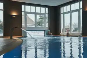 Pool Ein Hallenbad mit Wasserfall und großen Fenstern.