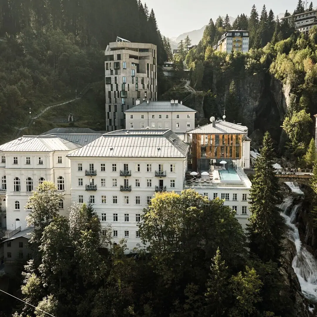 Eine Gruppe von Gebäuden mit Bäumen und Bergen im Hintergrund.