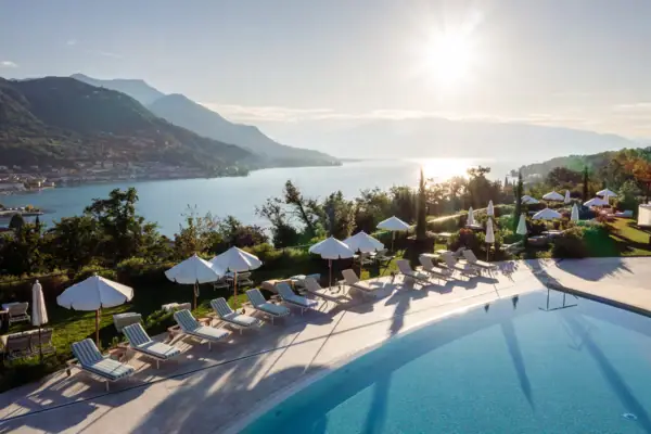 Panorama-Terrasse mit Poolblick am Gardasee Blick über den Poolbereich des A-ROSA Gardasee mit Sonnenschirmen und Panoramablick auf den See und die Berge.