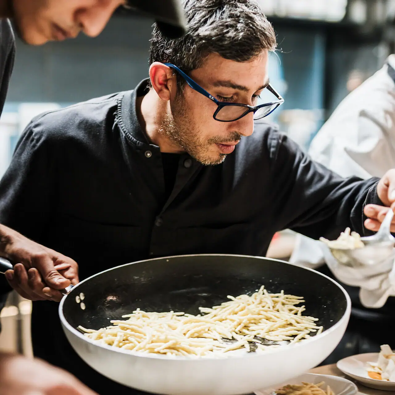 Incentives am Gardasee Ein Mann in einem schwarzen Hemd kocht Essen.