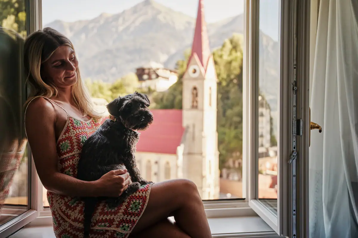 Eine Frau sitzt mit einem Hund auf einer Fensterbank.