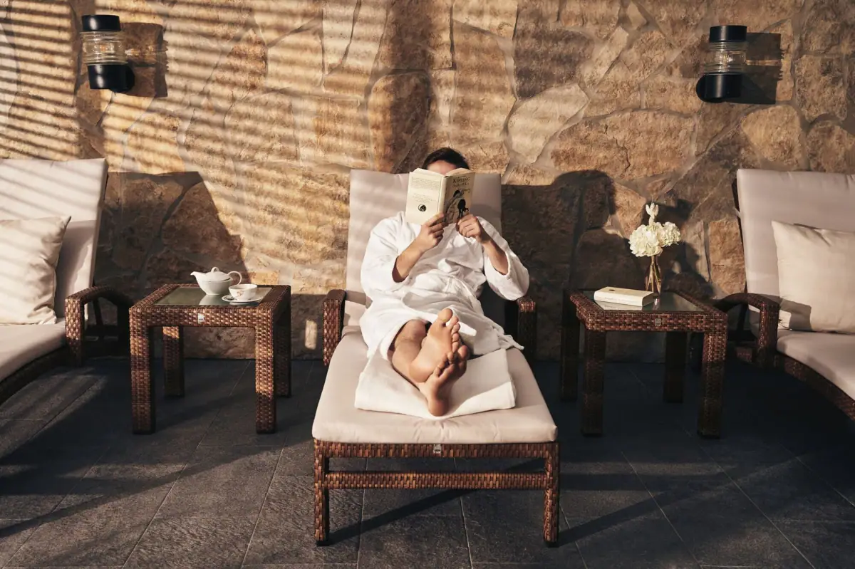 Eine Person liest ein Buch auf einem Liegestuhl.