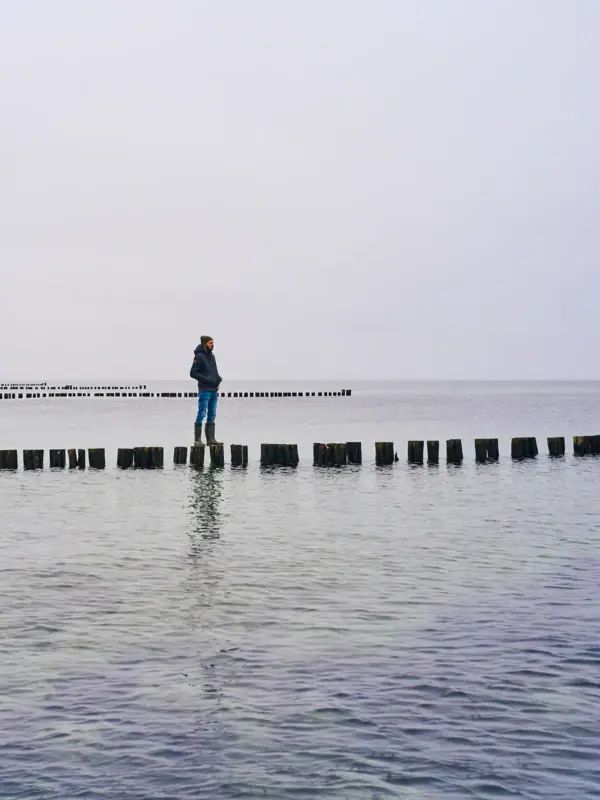 Eine Person steht auf einem Baumstamm im Wasser.