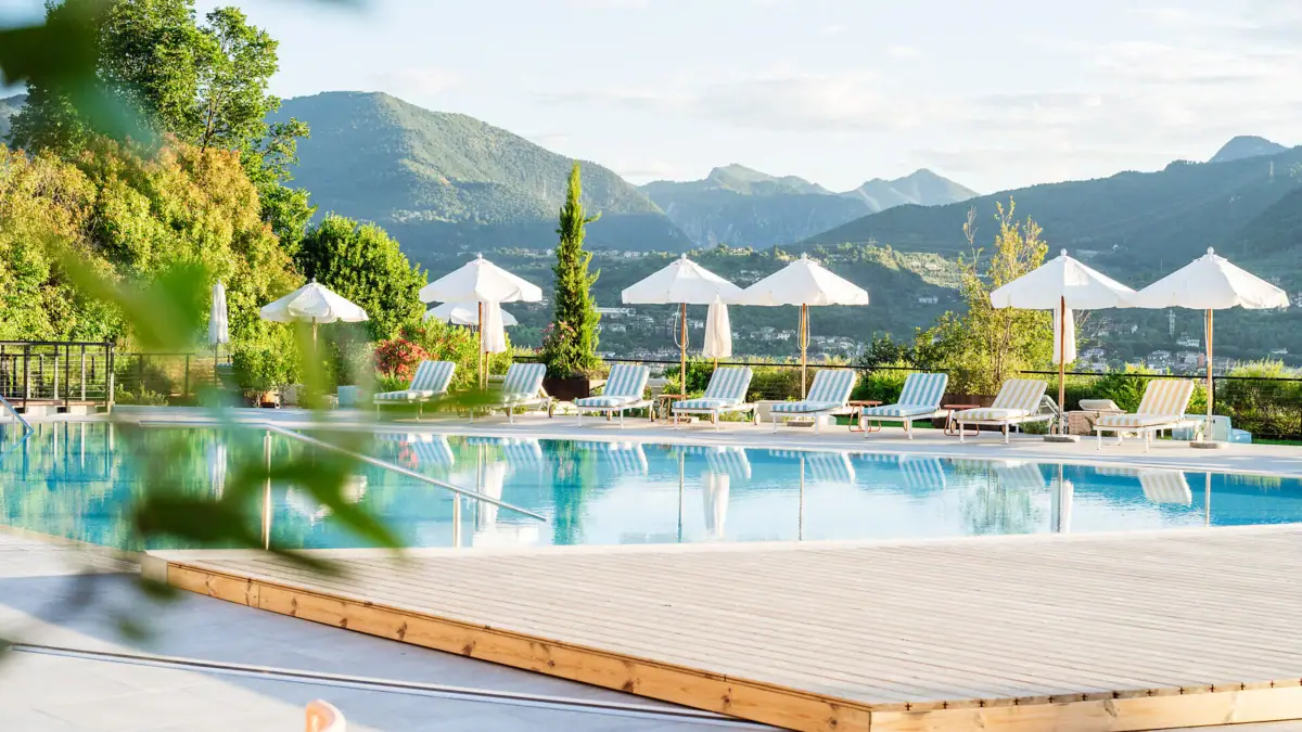 Gartenpool im A-ROSA Gardasee Ein Pool mit Liegestühlen und Sonnenschirmen.