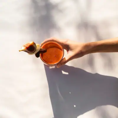 Vital Bar Eine Hand hält ein Glas Smoothie.