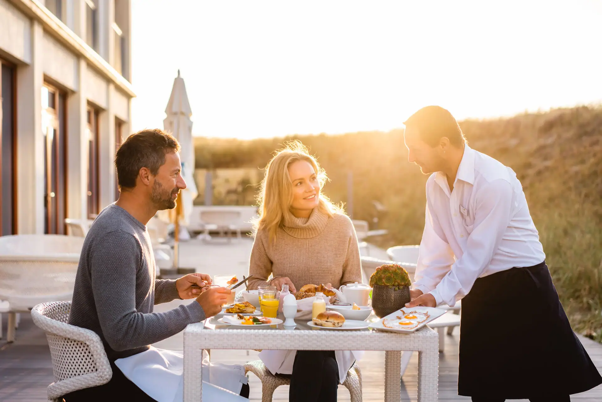 Frühstück auf der Terrasse Eine Gruppe von Menschen isst an einem Tisch.