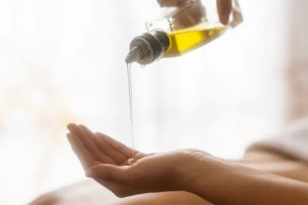 Massageöl Eine Person gießt Öl auf ihre Hand.
