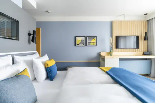 Zimmer A-ROSA Travemünde Ein modernes Hotelzimmer mit einem Bett, einem Schreibtisch und einem Fernseher.