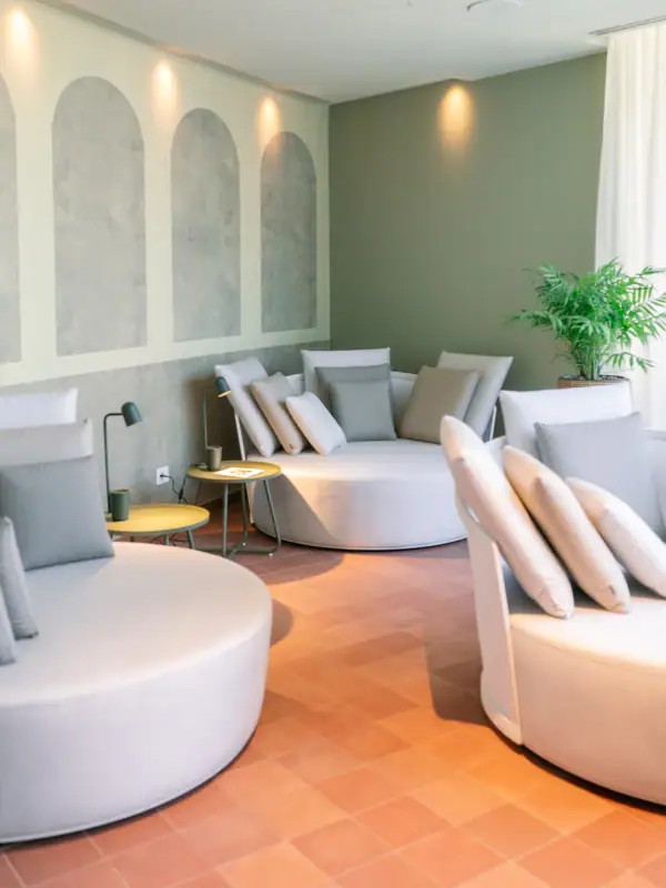 Ein Raum mit runden weißen Sofas und einer Pflanze.