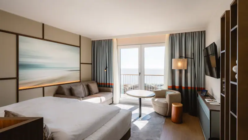 Doppelzimmer Meerblick Zimmer mit Bett und Couch im modernen Design.