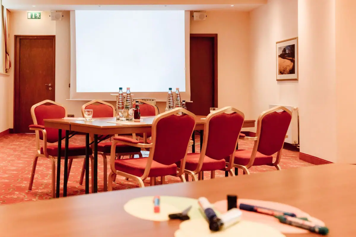 Tagungsraum mit Beamer Ein Raum mit einem Tisch und Stühlen.