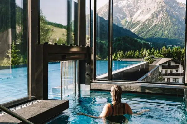 Eine Frau in einem Pool mit Bergen im Hintergrund.