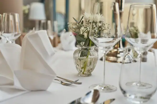 Ein Tisch mit Gläsern und einer Vase mit Blumen.