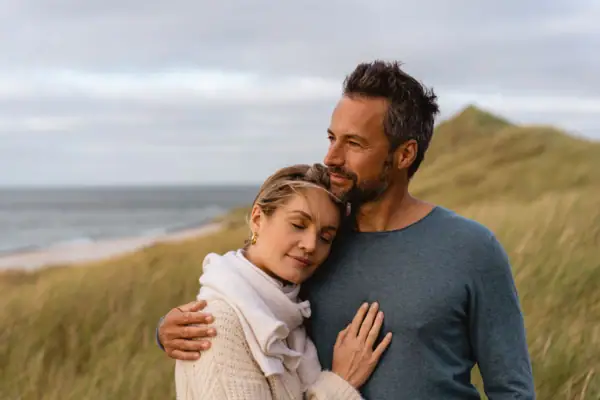 Dünen Ein Mann und eine Frau umarmen sich auf einer Wiese.