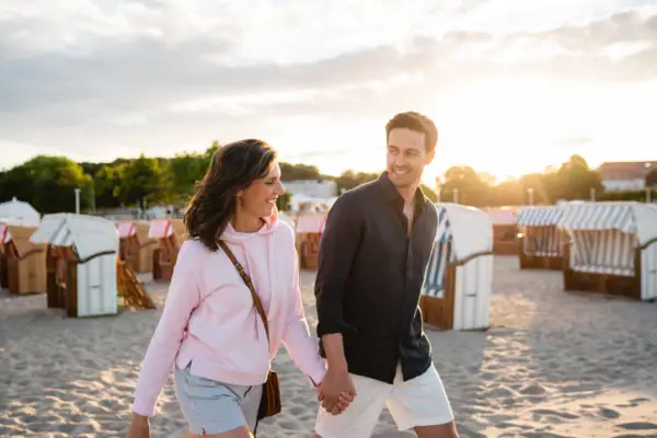 Paar am Strand Ein Mann und eine Frau halten sich an einem Strand an den Händen.