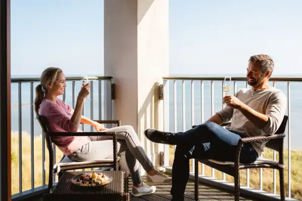 Balkon Ein Mann und eine Frau sitzen mit Getränken auf einer Terrasse.