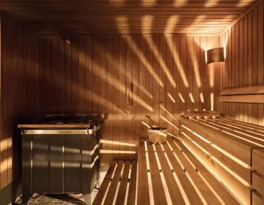 Holzsauna mit Sonnenlicht, das durch die Wände scheint.